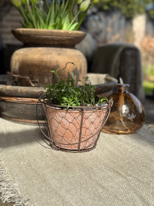 Terracotta bloempot in gaasmand met hengsel